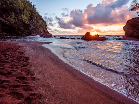 Discover the stunning sunrise over Kaihalulu Beach's unique red sands in Hana, Hawaii.